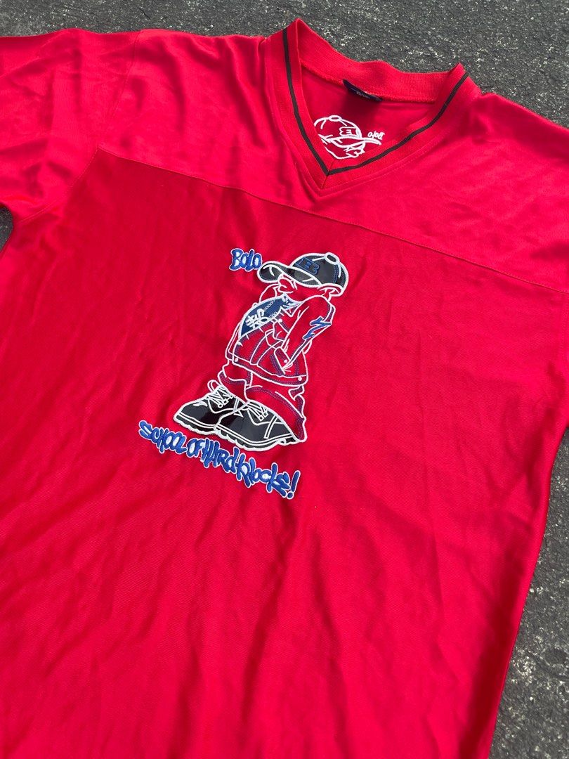 Ruff Ryders Bolo Graphic T-shirt (Category: Tshirts & Polo Shirts ) located in Manila. Submitted by alxanderctlan (Listing ID 1413508835, Image 2). Description: - Red Ruff Ryders T-shirt - Features a Bolo graphic on the front - V-neck design - Black stripes on sleeves and collar - Graphic of a person wearing a cap - Brand logo on collar - Back of shirt has cap graphic and "SOHK" logo.