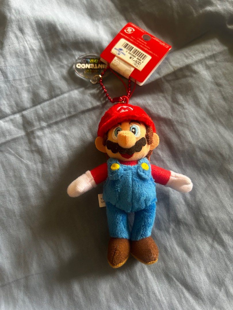 Super Nintendo World Mario Plush Keychain (Category: Character Goods) located in Taguig. Submitted by tidytitan (Listing ID 1413476514, Image 2). Description: - Authentic Mario plush keychain from Super Nintendo World. - Features Mario in his iconic red cap and blue overalls. - Includes attached tag. - Ideal for Nintendo and Mario collectors. - Perfect as a bag charm or a fun addition to your collection..