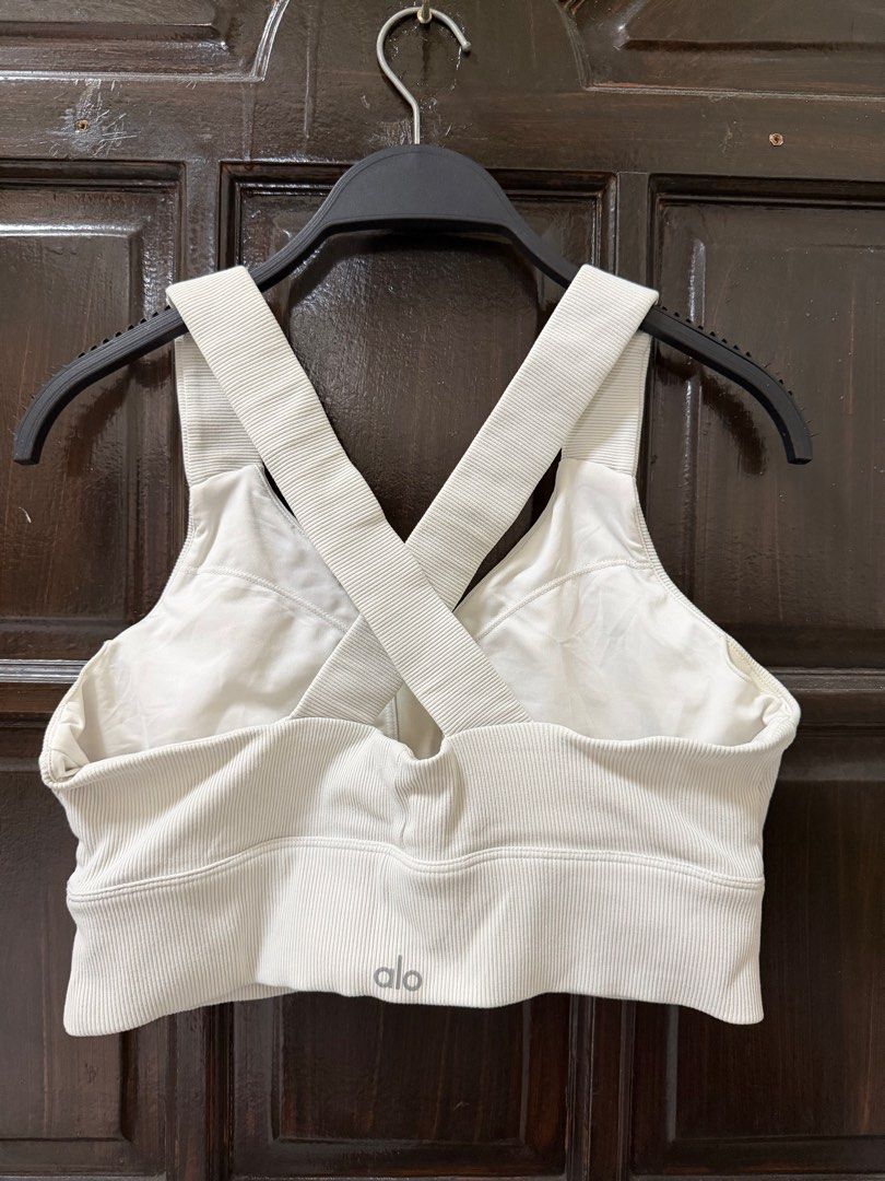 Alo Emulate Bra (Category: Activewear) located in Manila. Submitted by haveago0dthrift (Listing ID 1413793347, Image 3). Description: - Alo Yoga sports bra - Size: L - Features: Ribbed texture, crossback design, V-neck - Color: Light neutral (off-white) - Design: Alo logo on front - Origin: Made in Vietnam - Fit: Supportive -Width 28-34 -Length 14.