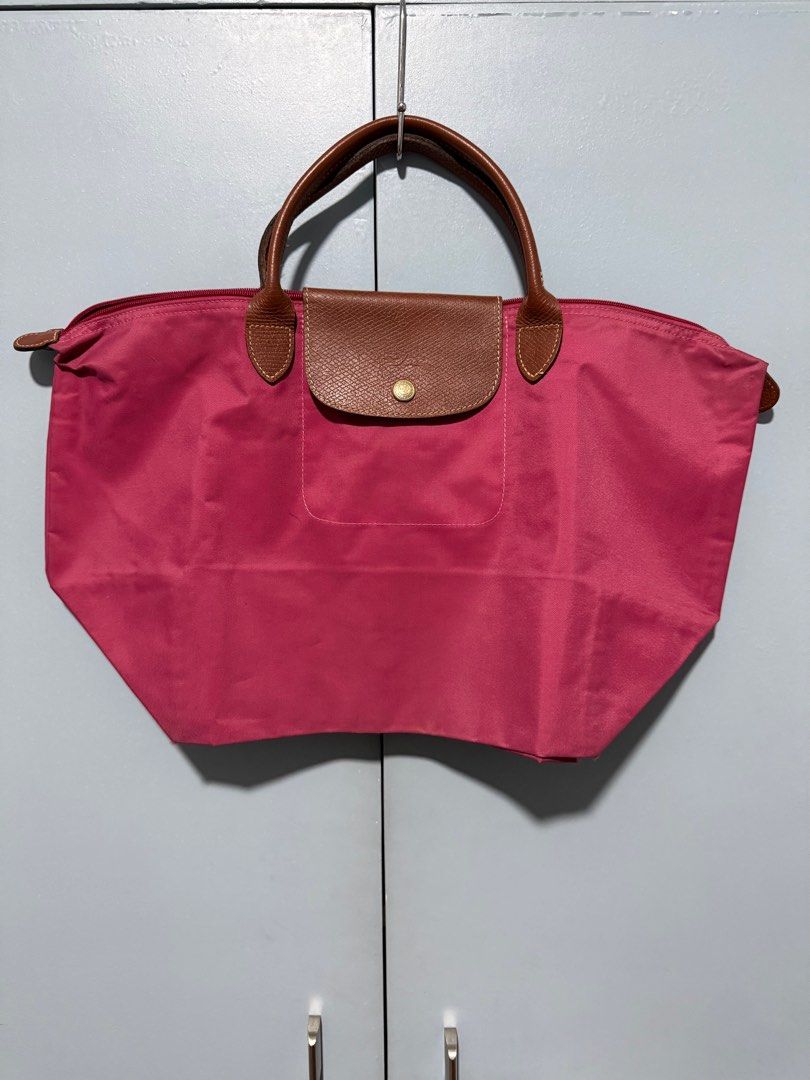 Longchamp Le Pliage Tote Bag (Category: Luxury Bags & Wallets) located in Quezon City. Submitted by amogz (Listing ID 1413737407, Image 1). Description: - Authentic Longchamp Le Pliage tote bag - Vibrant pink color - Brown leather flap and handles - Snap closure - Longchamp logo on zipper pull - White interior with small pocket - Made in China.