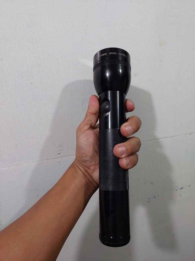 Maglite Flashlight (Category: Everything Else Others) located in Quezon City. Submitted by jpnvintageonline (Listing ID 1413780788, Image 3). Description: - Black Maglite flashlight - Textured grip for secure handling - Simple push-button on/off switch - Features the Maglite brand name - Shows size and shape in hand.