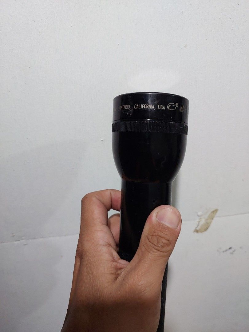 Maglite Flashlight (Category: Everything Else Others) located in Quezon City. Submitted by jpnvintageonline (Listing ID 1413780788, Image 2). Description: - Black Maglite flashlight - Textured grip for secure handling - Simple push-button on/off switch - Features the Maglite brand name - Shows size and shape in hand.