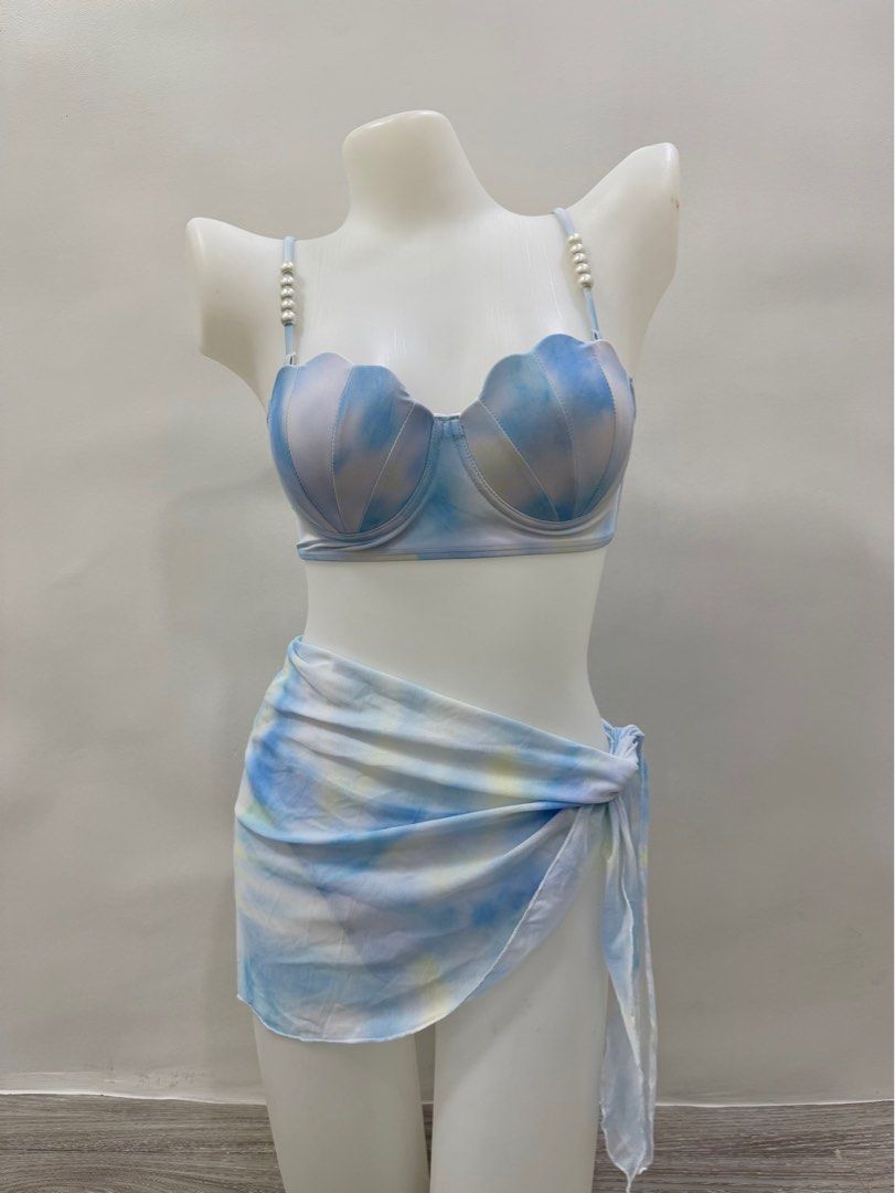Mermaid Shell Two-Piece Swimsuit with Sarong (Category: Bikinis & Swimsuits) located in Taguig. Submitted by gelpingol (Listing ID 1413821957, Image 2). Description: - Mermaid shell bikini set - Can fit to S-M - Features pearl-detailed straps - Includes bikini top, bottom, and matching sarong - Blue and white tie-dye fabric - Scalloped edge on top - Adjustable straps - Sarong can be styled in multiple ways.