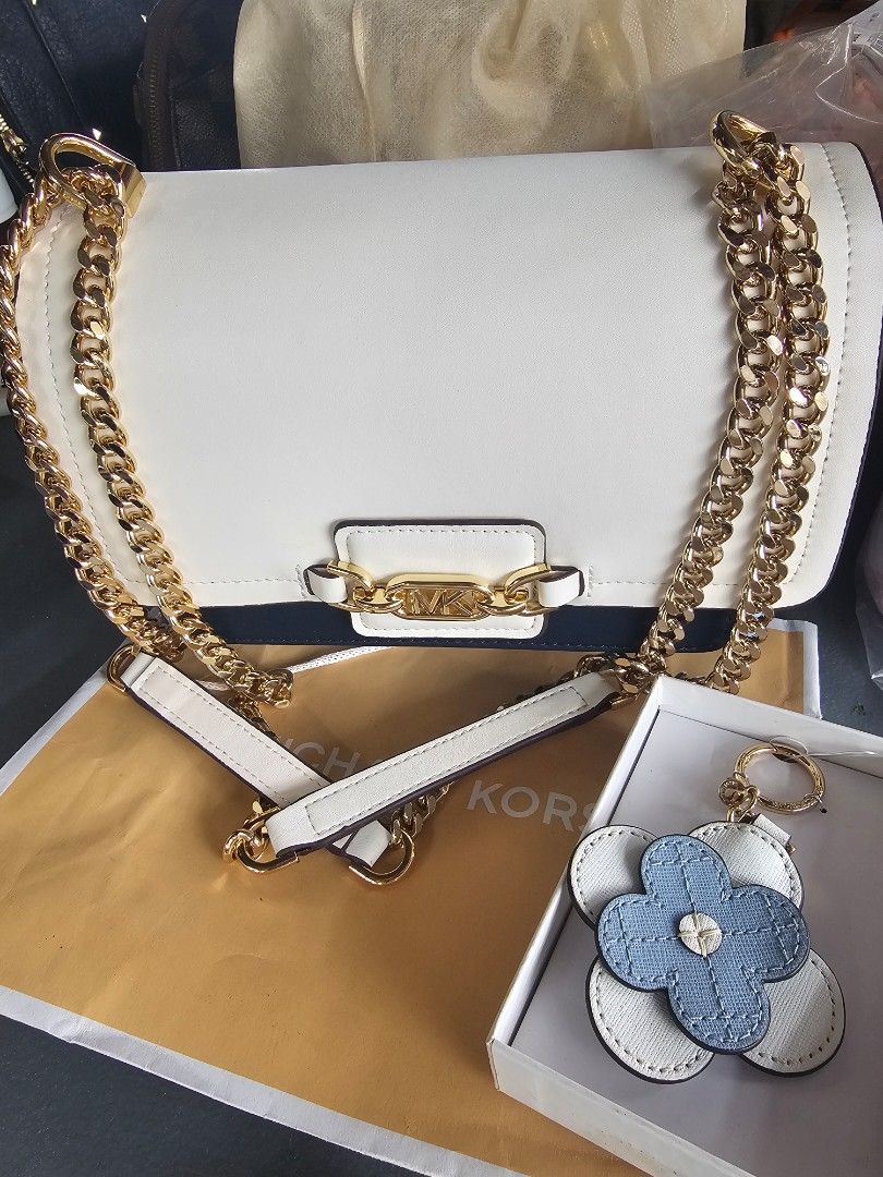 Michael Kors White Chain Shoulder Bag (Category: Luxury Bags & Wallets) located in Cavite. Submitted by thalitz40 (Listing ID 1413760793, Image 1). Description: - Brand new Michael Kors shoulder bag - Elegant white design - Features a stylish gold chain and clasp with the Michael Kors logo - Includes a detachable strap for versatile wear - Adorned with a charming flower-shaped keychain - Comes with the original box.