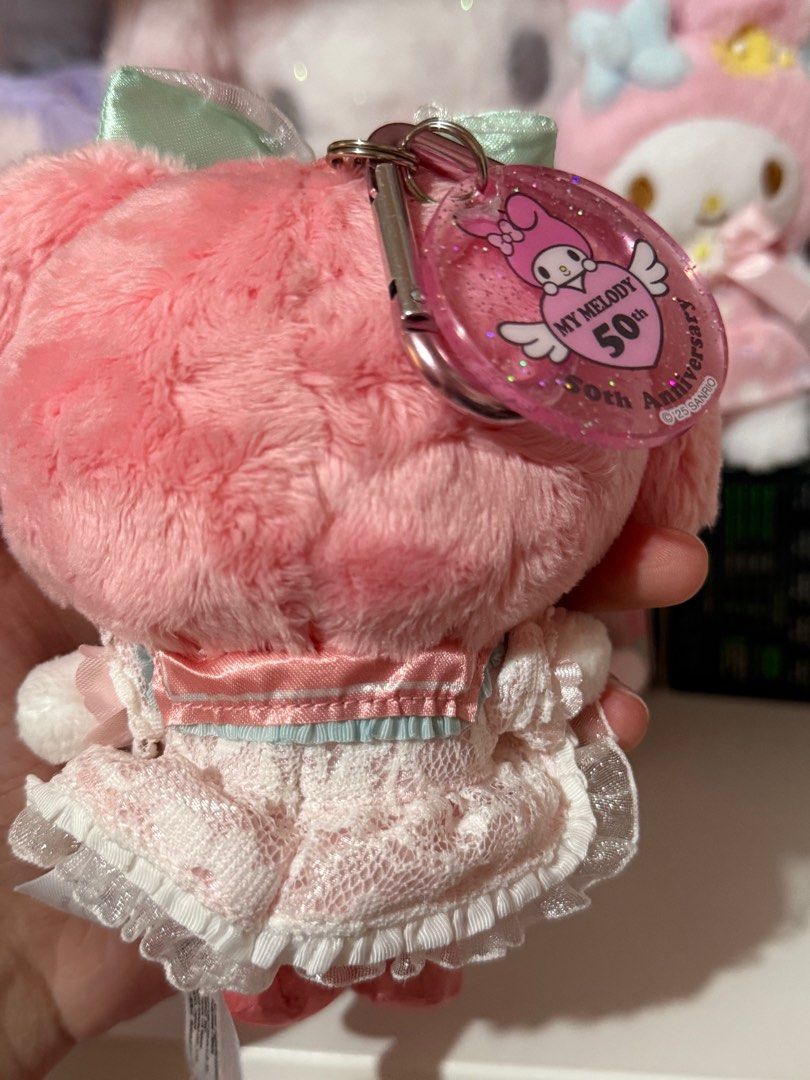 My Melody 50th Anniversary Charm (Category: Character Goods) located in Bocaue. Submitted by yncheoli (Listing ID 1413669391, Image 3). Description: - My Melody 50th Anniversary Plush - Features a cute pink plush design - Includes matching dress and bow - Comes with a convenient keychain - Collectible item for My Melody fans - Tag showcases different outfits.