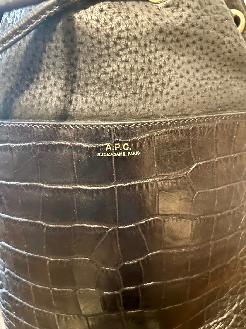 A.P.C. Black Bucket Bag (Category: Luxury Bags & Wallets) located in Quezon City. Submitted by asiaco (Listing ID 1413912430, Image 2). Description: Black bucket bag from A.P.C. Features a drawstring closure and a shoulder strap. The bag has a textured upper section and a crocodile-embossed lower section. The interior includes a zippered pocket. A.P.C. logo is visible on the front of the bag. Very nice. .