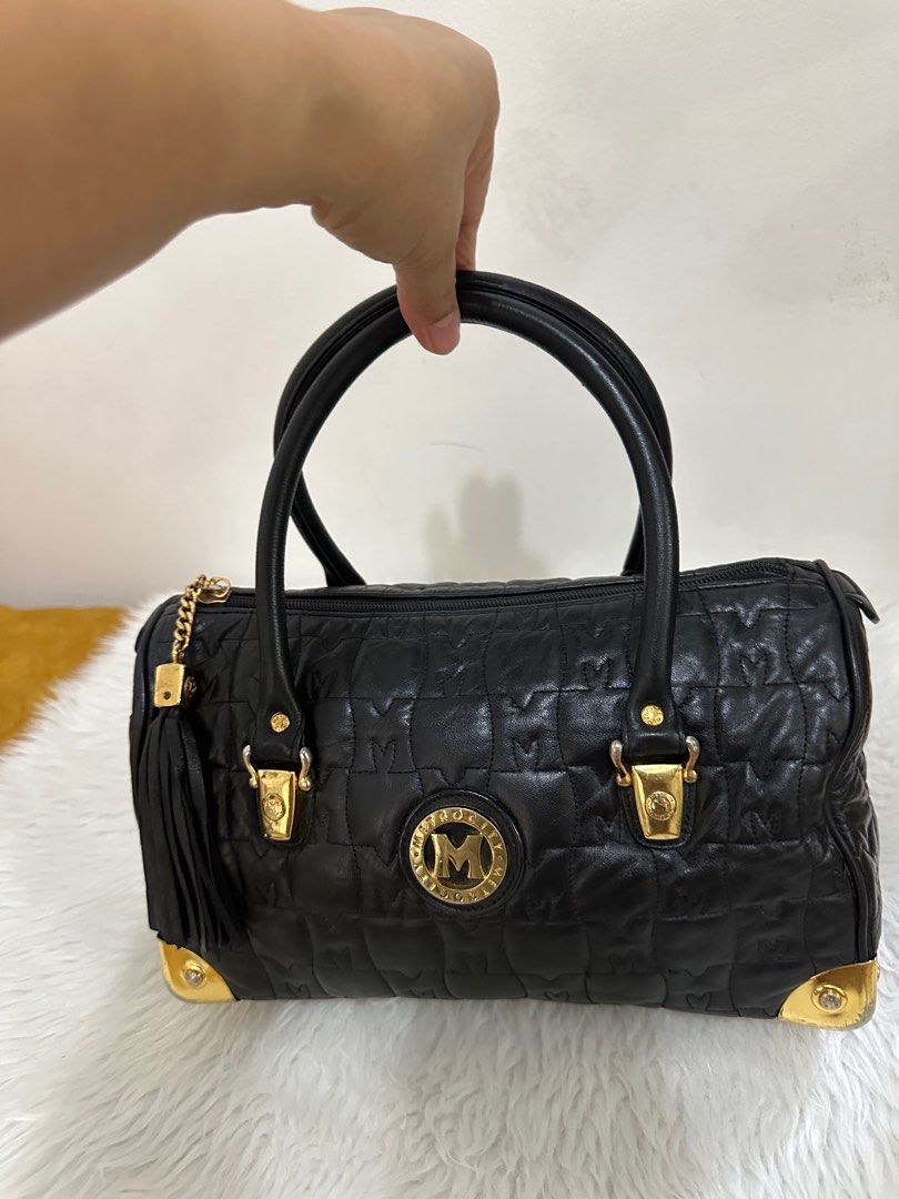 Metrocity Black Handbag (Category: Luxury Bags & Wallets) located in Antipolo. Submitted by jlonline_1207 (Listing ID 1414035937, Image 1). Description: Black Metrocity handbag with gold-tone hardware. Features a quilted design with the Metrocity logo prominently displayed. Includes a top handle and a detachable tassel. The bag has a zip closure and gold accents on the corners. The interior lining is black. Now sale.
