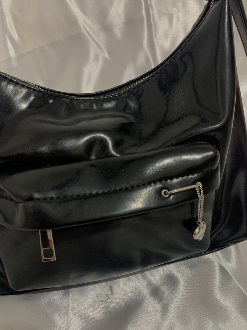 TALA - Black Shoulder Bag with Heart Charm (Category: Shoulder Bags) located in Manila. Submitted by ayarayaaa (Listing ID 1413939961, Image 2). Description: - Sleek black shoulder bag - Glossy finish - Front pocket with silver zipper - Decorative heart charm - Long, adjustable strap - Smooth, possibly synthetic material.