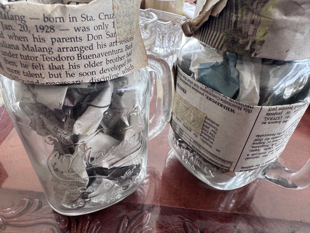Vintage Mason Jar with Handle EACH (Category: Food Organization & Storage) located in Manila. Submitted by decluterthings888 (Listing ID 1413881817, Image 2). Description: - glass jar no cover good for coffee or drinks - Features classic Mason design - Filled with old newspaper clippings - Clear glass body - Includes handles for easy carrying - Ideal for display or repurposing.