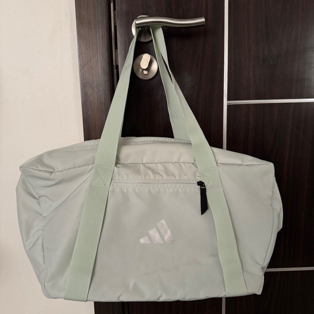 Adidas Training Duffle Bag (Category: Shoulder Bags) located in Manila. Submitted by declutterzoneee (Listing ID 1414104032, Image 1). Description: - Adidas training duffle bag - Light green color - Main compartment with zipper - Front pocket - Top handles and shoulder strap - Dark grey interior lining - Adidas logo on front.