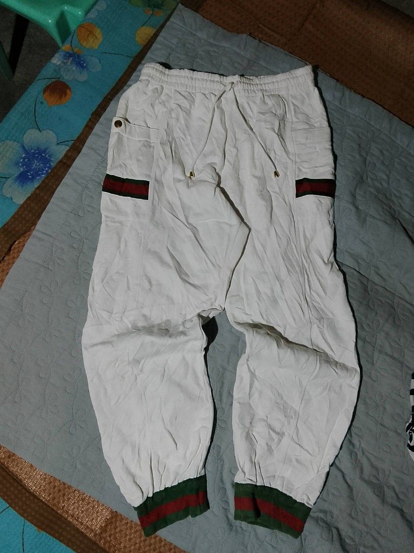 Gucci White Jogger Pants (Category: Joggers) located in Manila. Submitted by mamaluba2452761 (Listing ID 1414167147, Image 1). Description: - White gucci jogger pants - Green and red stripe detailing - Drawstring waist - Gold button accents - Small pocket with Gucci logo - Ribbed cuffs with green and red stripes - Size M.