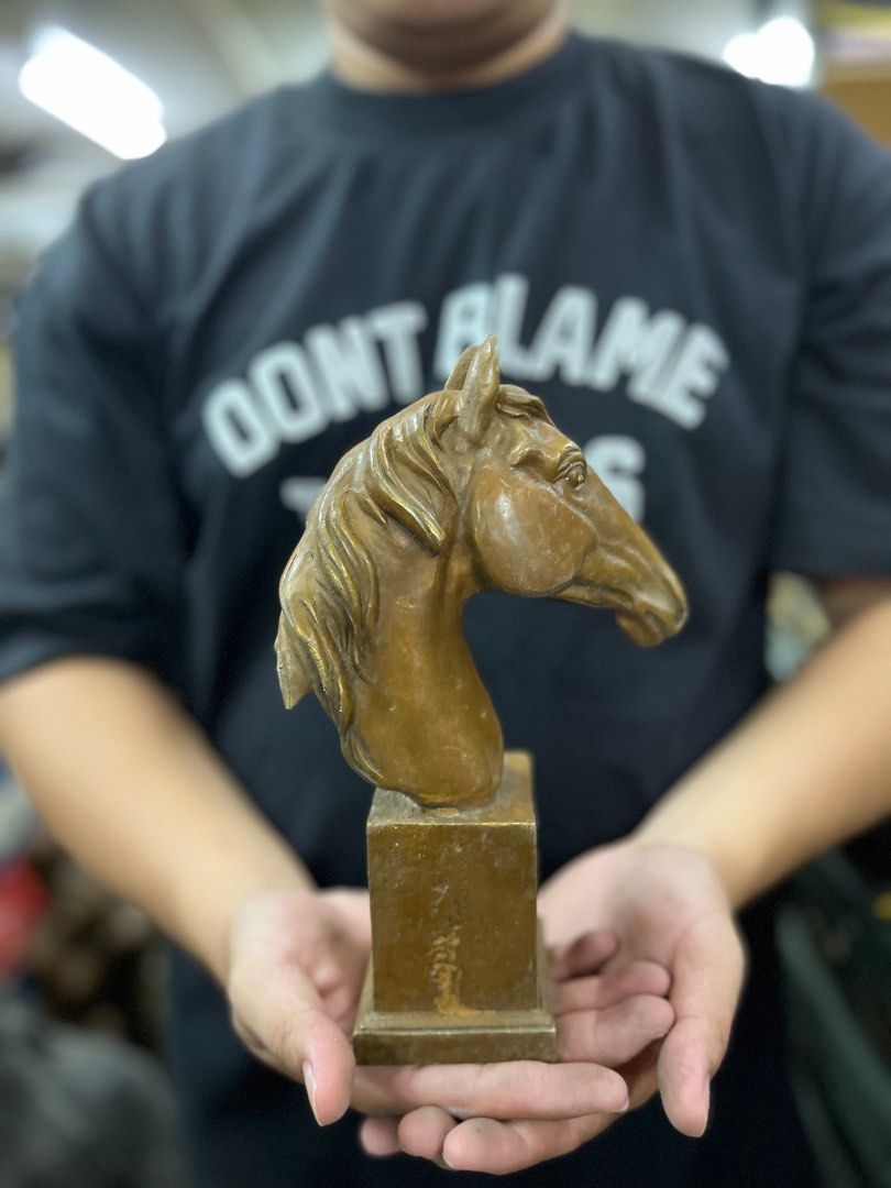 Horse Head Sculpture (Category: Other Home Decor) located in Manila. Submitted by vintage_styles_co (Listing ID 1414239232, Image 3). Description: Sculpture features a detailed horse head mounted on a rectangular base. The sculpture has a bronze-like finish. It is a decorative piece that would be a great addition to any home or office. The sculpture is held in the hands, showing its size and form..