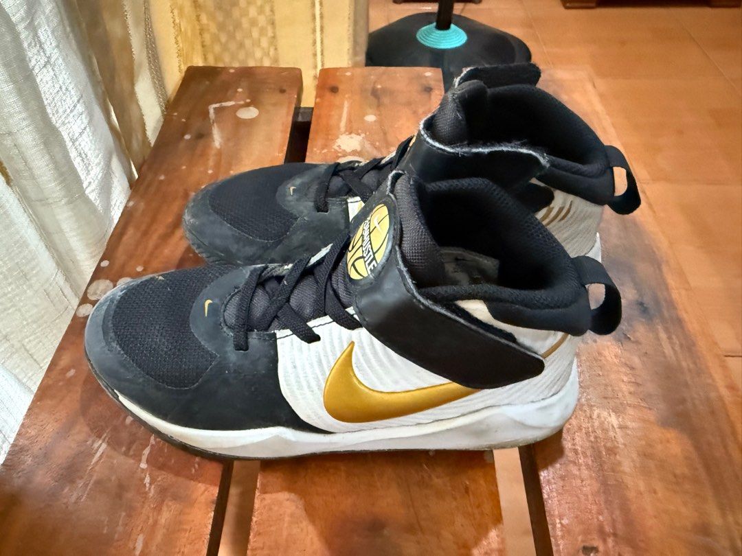 Nike High-Top Basketball Sneakers (Category: Babies & Kids Fashion) located in Quezon City. Submitted by krisallie (Listing ID 1414082010, Image 3). Description: - Nike high-top basketball sneakers - Black and white color scheme with gold accents - Hook-and-loop strap for secure fit - Nike swoosh logo - Designed for basketball.