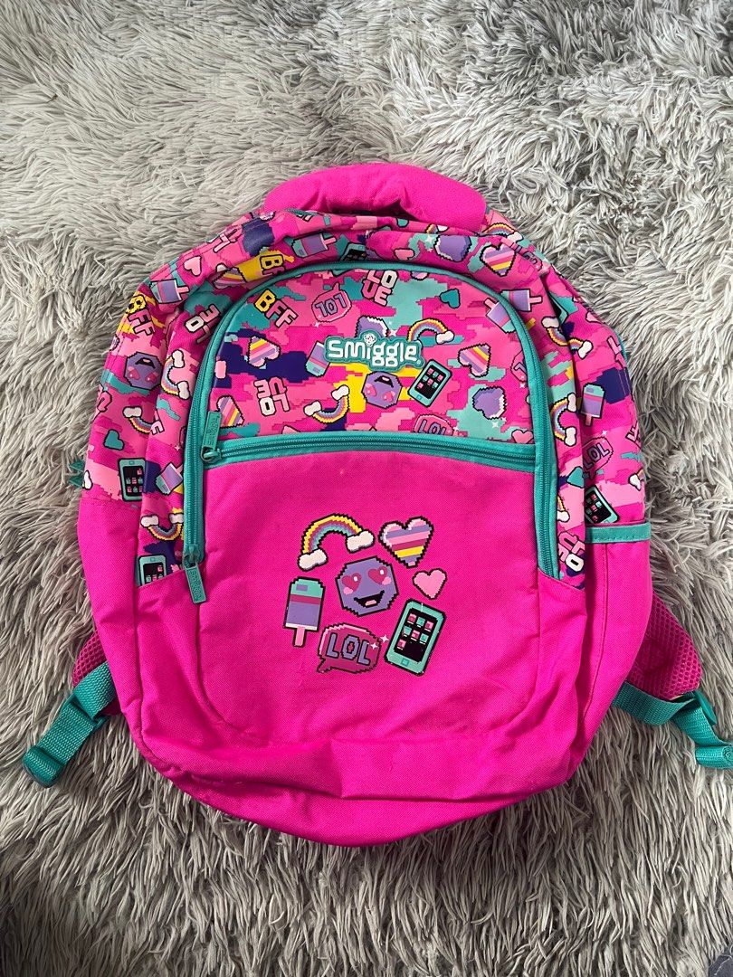 Smiggle Backpack (Category: Backpacks) located in Muntinlupa City. Submitted by caistuff (Listing ID 1414130244, Image 1). Description: - Vibrant pink Smiggle backpack - Fun, colorful pattern - Main compartment with zipper - Front pocket with zipper - Padded shoulder straps - Top handle - Smiggle logo detail - Pink interior.