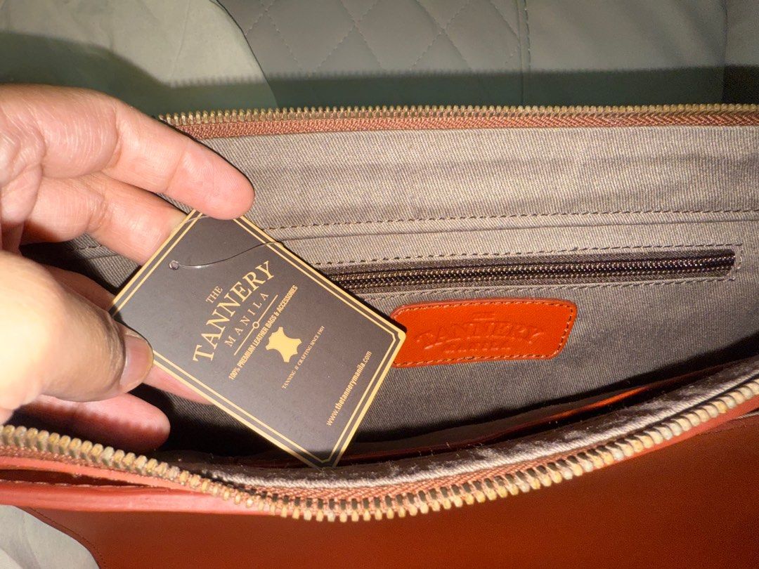 The Tannery Manila Leather Bag (Category: Luxury Bags & Wallets) located in Manila. Submitted by barbie.closet (Listing ID 1414192216, Image 3). Description: - Brand: The Tannery Manila - Material: Genuine Leather - Color: Reddish Brown - Closure: Zipper - Features: - Includes dust bag and original tags - Interior zippered pocket - Perfect for carrying essentials - Made with 100% premium leather Around 15” in width. Can fit MacBook Pro or any lap