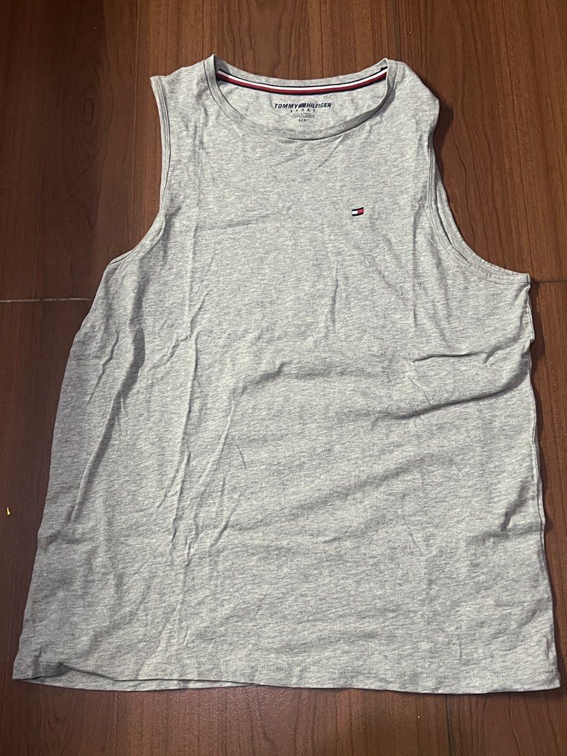 Tommy Hilfiger Grey Tank Top (Category: Activewear) located in Taguig. Submitted by matty_28 (Listing ID 1414200002, Image 1). Description: -Willing to VC for further Checking Gray tank top from Tommy Hilfiger. Features the brand's logo on the chest. The tank top has a round neckline with a red and white stripe detail. The back is plain gray. Made of a soft, cotton material..