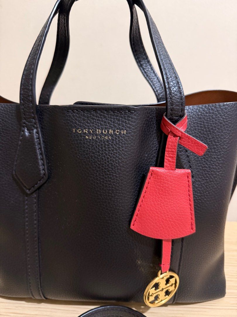 Tory Burch Perry Small Tote Bag (Guaranteed Original) (Category: Luxury Bags & Wallets) located in Davao. Submitted by abdullahal43824 (Listing ID 1414205004, Image 2). Description: - Tory Burch Perry Small Tote Bag - Black exterior, brown interior - Detachable shoulder strap - Red and gold charm - Top handle - Zipper closure - Small interior pocket - Tory Burch logo on front.