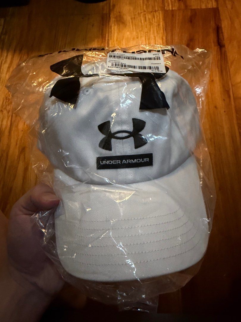 Under Armour Branded Hat (Category: Caps & Hats) located in San Fernando. Submitted by decluttermigs (Listing ID 1414157636, Image 1). Description: - Authentic Under Armour hat - Features the Under Armour logo - Color: White hat with black logo - Size: One size fits all - Condition: Brand new, still in original packaging.