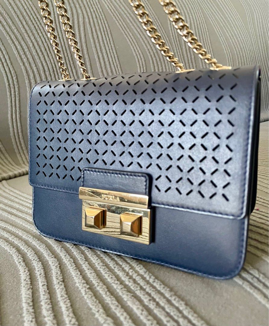 Furla Metropolis Perforated Crossbody Bag (Category: Luxury Bags & Wallets) located in Angeles City. Submitted by annedrc (Listing ID 1414264146, Image 3). Description: - Authentic Furla Metropolis crossbody bag - Navy blue leather exterior - Stylish gold chain strap and clasp (two-way) - Unique perforated design on front flap - Includes Furla label - Comes with care instructions card.
