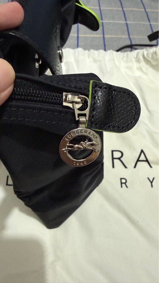 Longchamp Le Pliage Handbag (Category: Luxury Bags & Wallets) located in Quezon City. Submitted by pattyeval (Listing ID 1414253408, Image 3). Description: - Black Longchamp Le Pliage handbag - Flap closure with button - Leather handles - Zipper closure with Longchamp logo charm - Spacious interior - Includes Zalora Luxury dust bag and box - Can provide proof of purchase.
