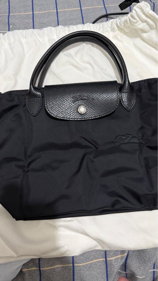 Longchamp Le Pliage Handbag (Category: Luxury Bags & Wallets) located in Quezon City. Submitted by pattyeval (Listing ID 1414253408, Image 2). Description: - Black Longchamp Le Pliage handbag - Flap closure with button - Leather handles - Zipper closure with Longchamp logo charm - Spacious interior - Includes Zalora Luxury dust bag and box - Can provide proof of purchase.