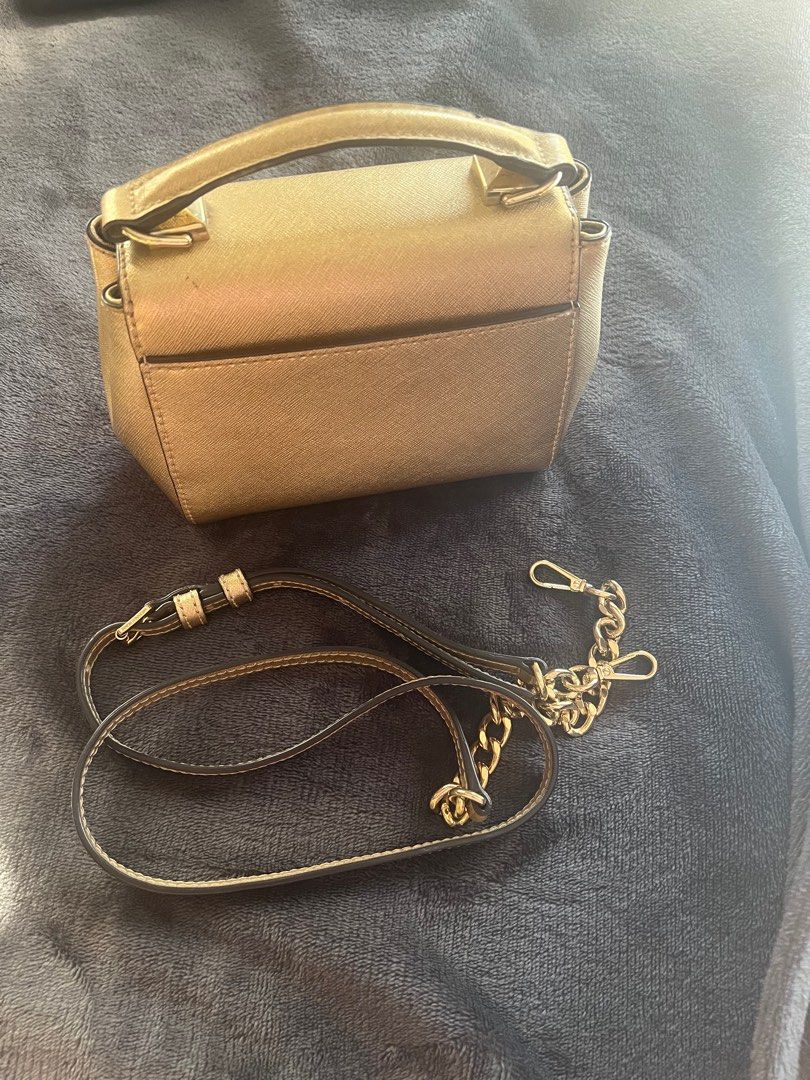 Michael Kors Gold Crossbody Bag (Category: Luxury Bags & Wallets) located in Guiguinto. Submitted by tearsayrin (Listing ID 1414314235, Image 3). Description: - Michael Kors crossbody bag in metallic gold. - Top handle and detachable chain strap. - Flap closure with studded accents. - Interior pocket. - Detachable strap for shoulder or crossbody wear..