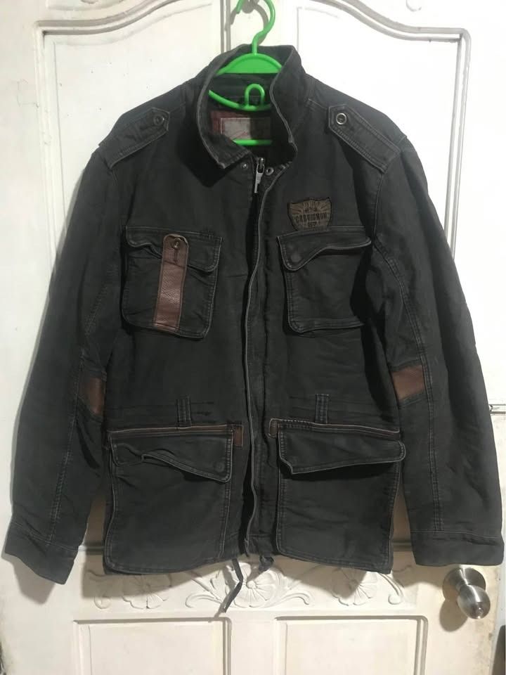 Vintage Chevignon Jacket - Size Large (Category: Coats, Jackets and Outerwear) located in Dasmarinas. Submitted by shuranotoki (Listing ID 1414462561, Image 1). Description: - Chevignon jacket in size L - Dark color with brown leather accents - Features leather accents on pockets and sleeves - Multiple pockets for storage - Full zipper closure - Drawstring waist for adjustable fit - Quilted lining for warmth and comfort - Chevignon brand logo on 