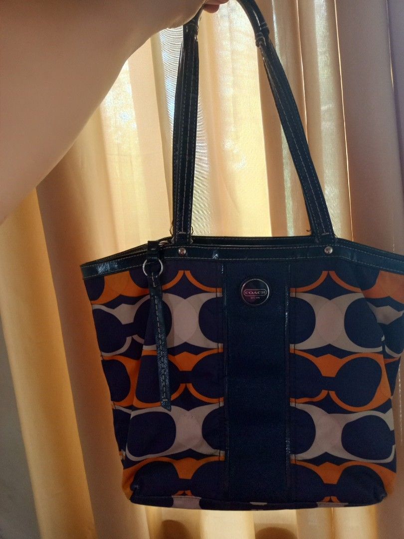 Coach Signature Tote Bag (Category: Luxury Bags & Wallets) located in Pasig City. Submitted by karenrules (Listing ID 1414467618, Image 1). Description: - Authentic Coach tote bag - Signature pattern: navy, orange, and beige circles - Navy blue leather trim and handles - Zipper closure - Interior pockets - Coach logo on front - Includes tag: E1380-F23908.