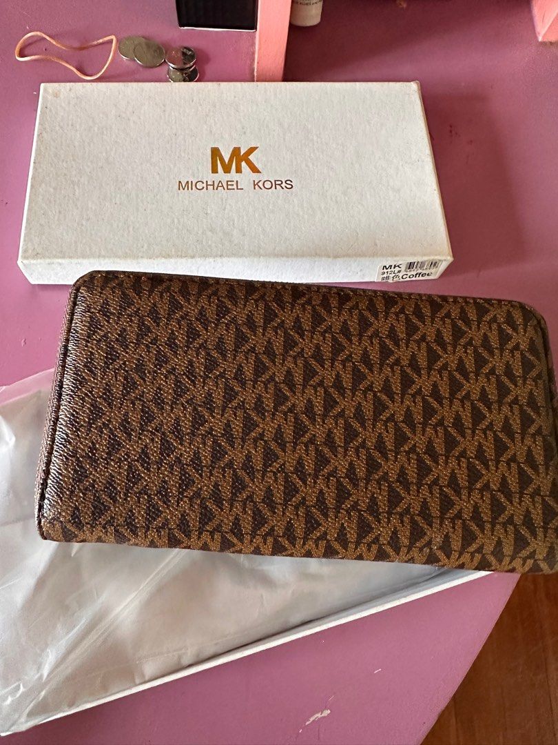 Michael Kors Zip Around Wallet (Class A) (Category: Wallets & Card holders) located in Tanza. Submitted by euniceericka (Listing ID 1414467296, Image 2). Description: - Authentic Michael Kors zip-around wallet (Class A) - Brown with iconic MK logo print - Multiple card slots - Zippered compartment - Gold-tone zipper and hardware - Interior: Orange - Includes original box - Signature detail on front - Never been used RFS: Decluttering .