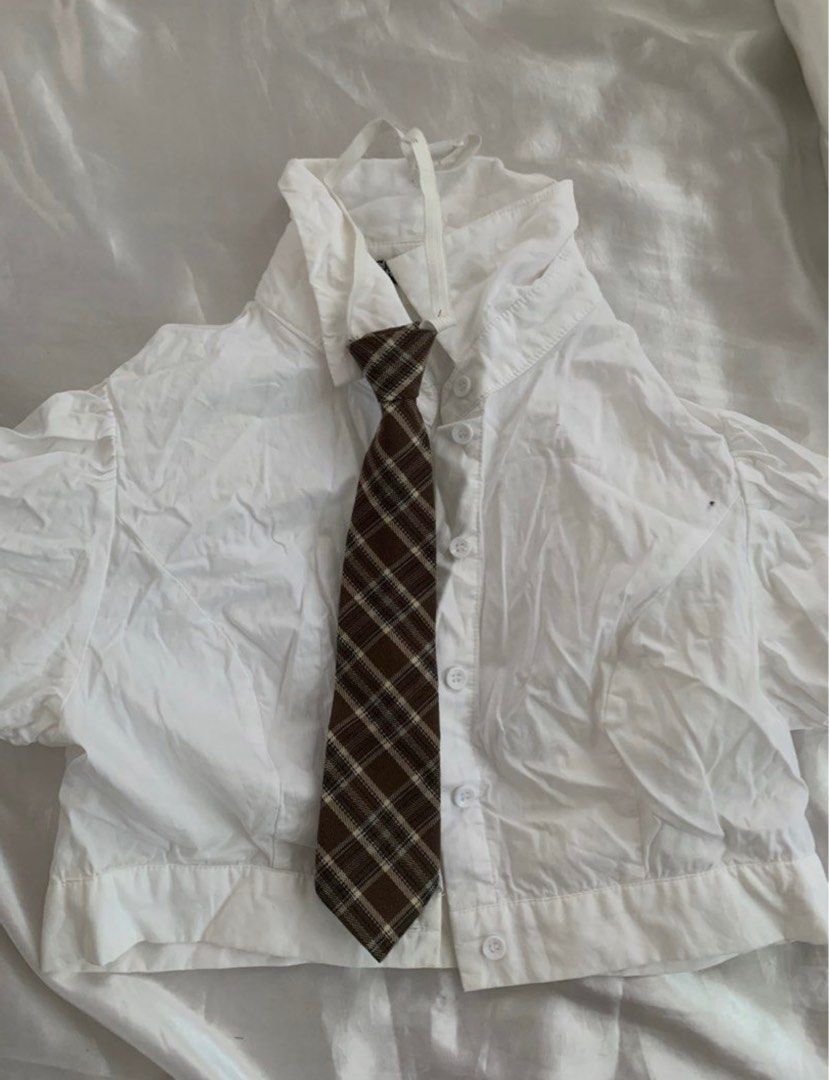 Shein White Shirt with Tie (Category: Shirts) located in Manila. Submitted by geecobra (Listing ID 1414519538, Image 1). Description: - Shein white cropped shirt - Includes a matching brown plaid tie - Size: M (EU 38, US 6) - Features button closures - Short sleeves with gathered shoulder detail - Comes with a collar - Versatile tie included.
