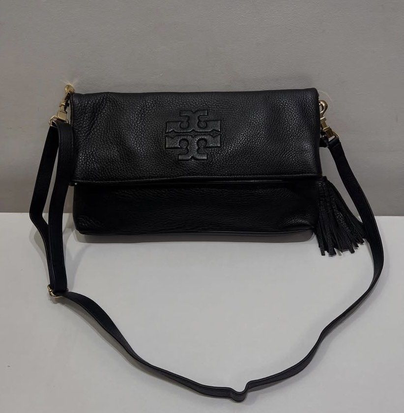 Tory Burch Bag (Thea Fold-over Crossbody) (Category: Luxury Bags & Wallets) located in Marikina City. Submitted by campdaisy_manila (Listing ID 1414494909, Image 2). Description: - Black Tory Burch Thea leather fold-over crossbody bag - Flap closure with Tory Burch logo - Tassel detail - Gold-tone hardware - Dimension in inches: L8 × W14 × D2.