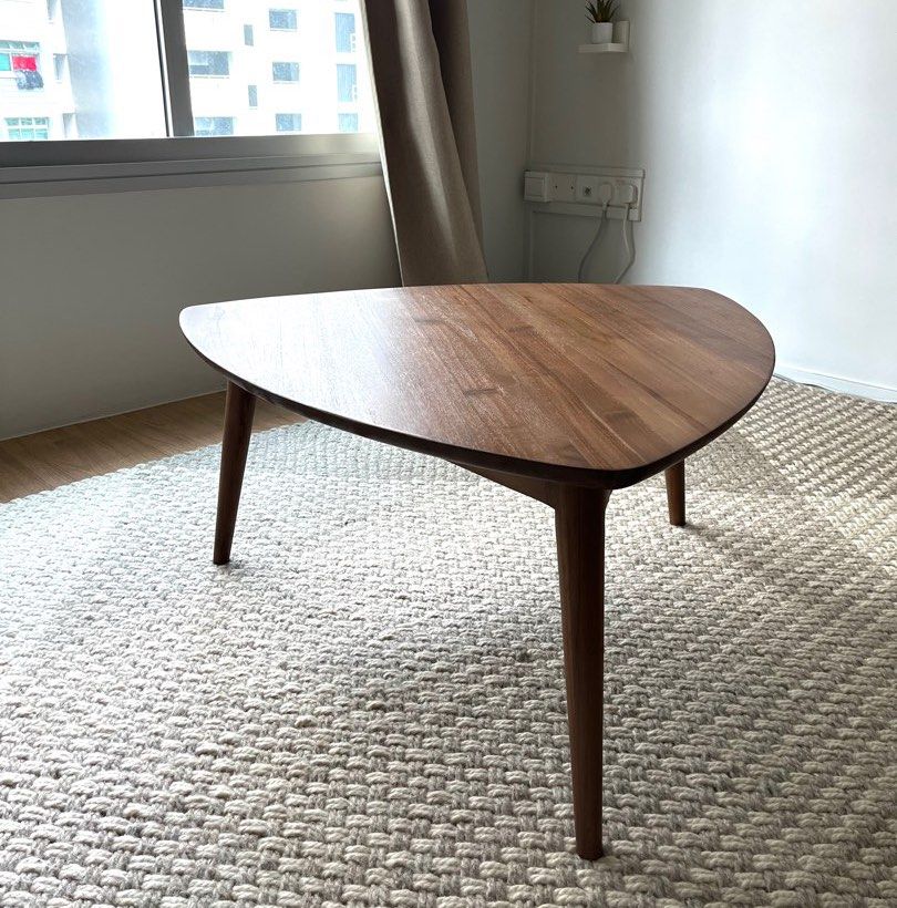 Triangular Solid Teak Coffee Table (Category: Tables & Sets) located in Singapore. Submitted by konicashoes (Listing ID 1414562257, Image 2). Description: Karpenter Vintage Tripod Teak Coffee Table An elegant designer coffee table by Karpenter, showcasing a distinctive triangular tripod silhouette. Expertly crafted from solid teak wood, the table features a rich, warm finish that highlights the natural grain and timeless beauty of the material. T
