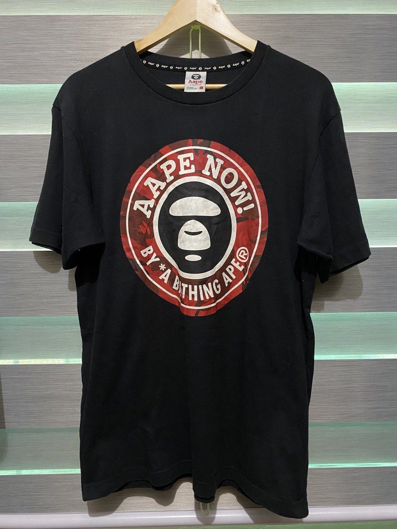 AAPE By A Bathing Ape T-shirt Size L (Category: Tshirts & Polo Shirts ) located in Butuan. Submitted by nielben13 (Listing ID 1465179809, Image 1). Description: - Brand: AAPE by A Bathing Ape - Color: Black with iconic red camo circle print and 'Aape Now!' text - Size: L (with branded neck tape) - Fit: Classic crew neck with short sleeves - Condition: Good overall condition, crisp graphics with no cracking.