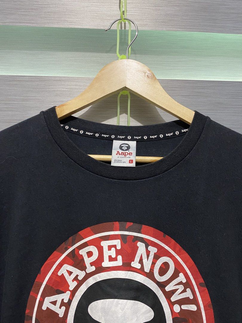 AAPE By A Bathing Ape T-shirt Size L (Category: Tshirts & Polo Shirts ) located in Butuan. Submitted by nielben13 (Listing ID 1465179809, Image 2). Description: - Brand: AAPE by A Bathing Ape - Color: Black with iconic red camo circle print and 'Aape Now!' text - Size: L (with branded neck tape) - Fit: Classic crew neck with short sleeves - Condition: Good overall condition, crisp graphics with no cracking.