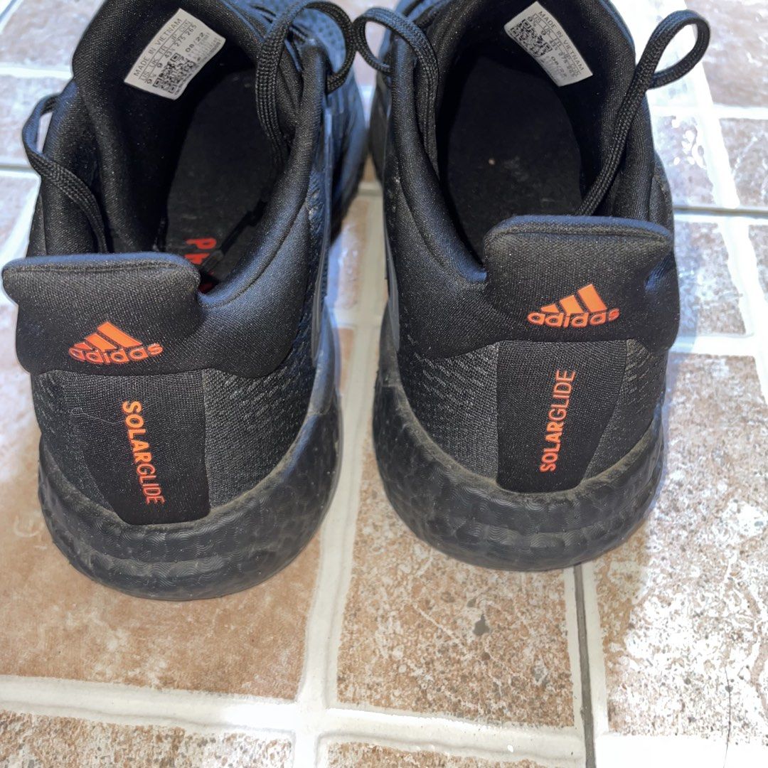 Adidas SolarGlide Black Night Metallic (Category: Sneakers) located in Valenzuela. Submitted by redanselmo (Listing ID 1465327973, Image 3). Description: - Brand: Adidas Solarglide - Color: Black with vibrant orange accents on the tongue and heel tab - Cushioning: Responsive Boost midsole for maximum comfort - Size: US 9.5 | UK 9 | FR 43 1/3 - Condition: Normal wear on soles and uppers from previous use - Perfect for daily runs or casual wear - S
