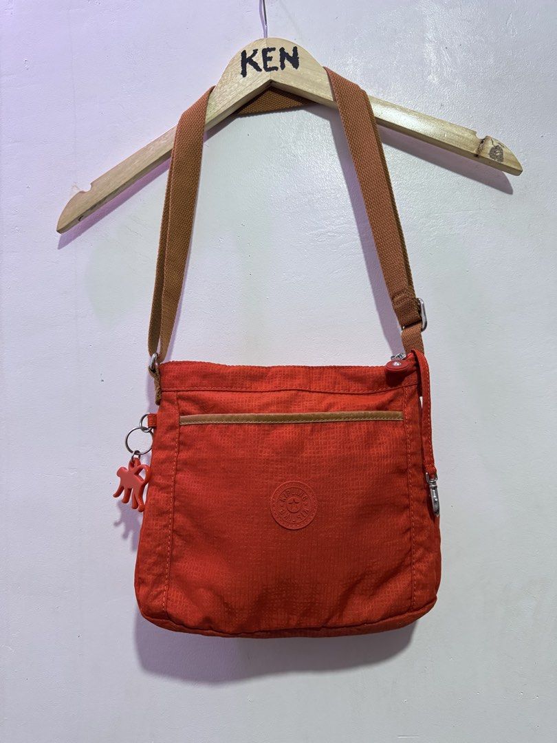 Authentic Kipling Moyelle Crossbody Sling Bag Orange (Category: Cross-body Bags) located in Manila. Submitted by esparciake75752 (Listing ID 1465305140, Image 2). Description: - Authentic Kipling crossbody bag in vibrant bright orange - Durable and lightweight nylon fabric with a roomy interior - Adjustable brown strap for comfortable wear - Secure top zip closure and front zipped pocket with tan piping - Includes the iconic matching orange monke