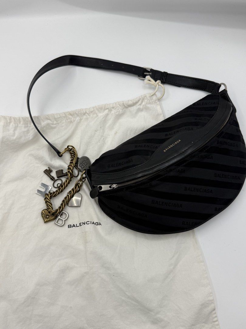Balenciaga bag (Category: Shoulder Bags) located in Caloocan City. Submitted by rossvault2 (Listing ID 1465227779, Image 2). Description: - Brand: Balenciaga - Style: Crescent sling bag or belt bag/body bag - Material: Black jacquard fabric with leather trim - Hardware: Gold-tone - Details: Includes attached charm chain (keys, heart, 'B' pendants) - Closure: Top zip - Interior: Black leather lining with branded open pocket - Strap: Adjustable lea