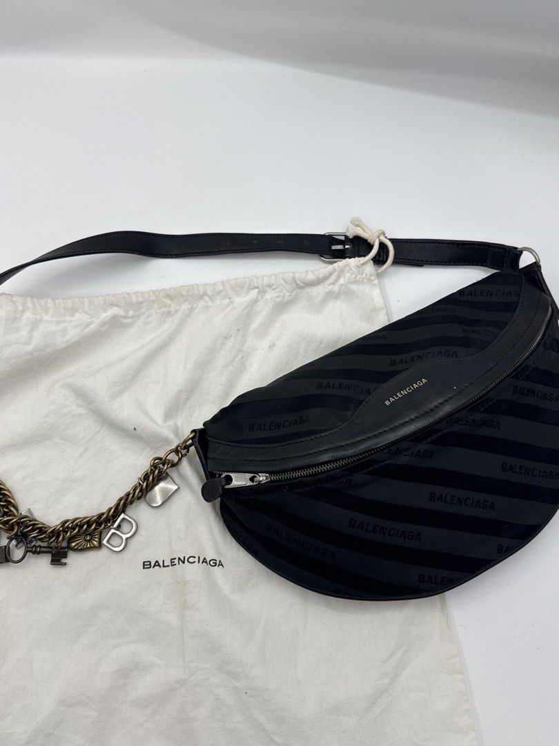 Balenciaga bag (Category: Shoulder Bags) located in Caloocan City. Submitted by rossvault2 (Listing ID 1465227779, Image 1). Description: - Brand: Balenciaga - Style: Crescent sling bag or belt bag/body bag - Material: Black jacquard fabric with leather trim - Hardware: Gold-tone - Details: Includes attached charm chain (keys, heart, 'B' pendants) - Closure: Top zip - Interior: Black leather lining with branded open pocket - Strap: Adjustable lea
