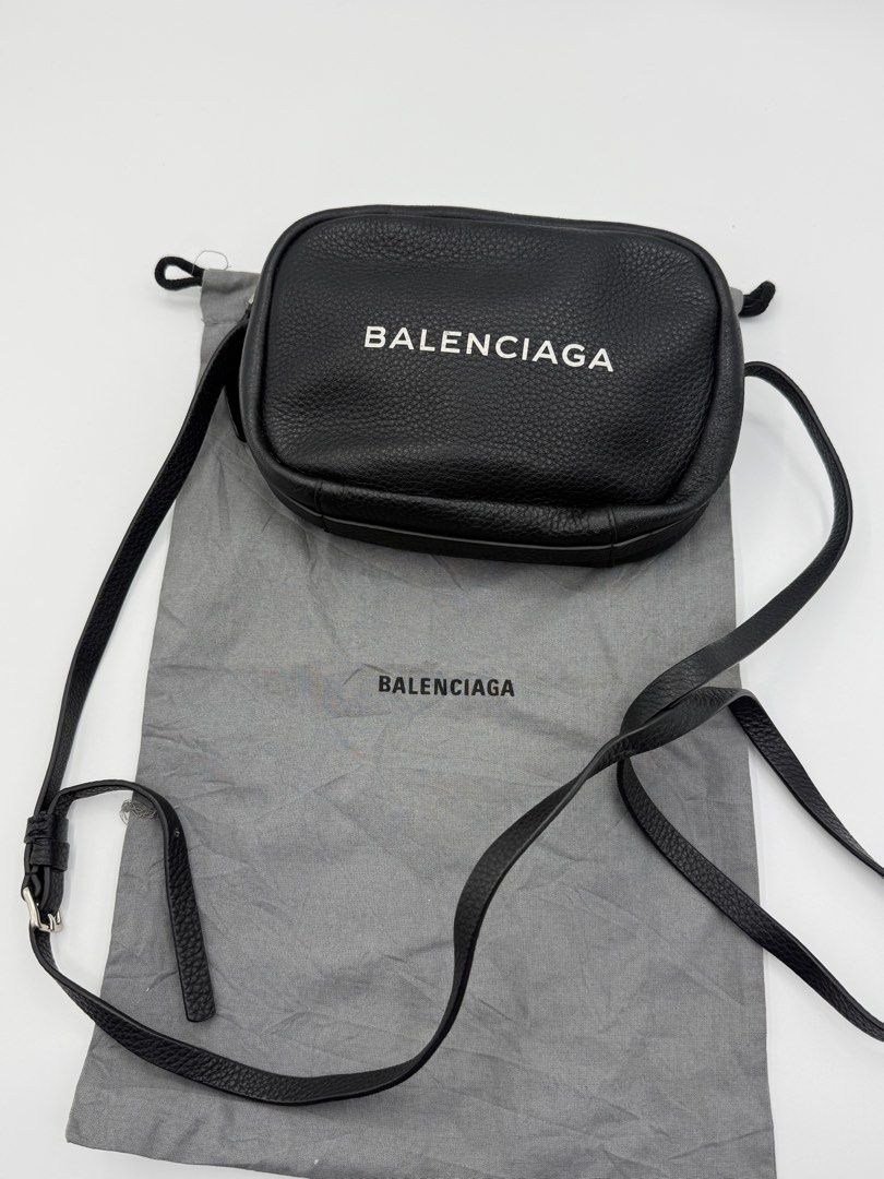 Balenciaga Everyday Camera Bag Black (Category: Cross-body Bags) located in Caloocan City. Submitted by rossvault2 (Listing ID 1465235636, Image 1). Description: - Balenciaga crossbody bag - Black textured leather with white front logo - Adjustable thin shoulder strap with silver-tone hardware - Secure top zip closure - Clean interior featuring a small slip pocket and card slots - Includes original grey Balenciaga dust bag - Condition: Excellent/