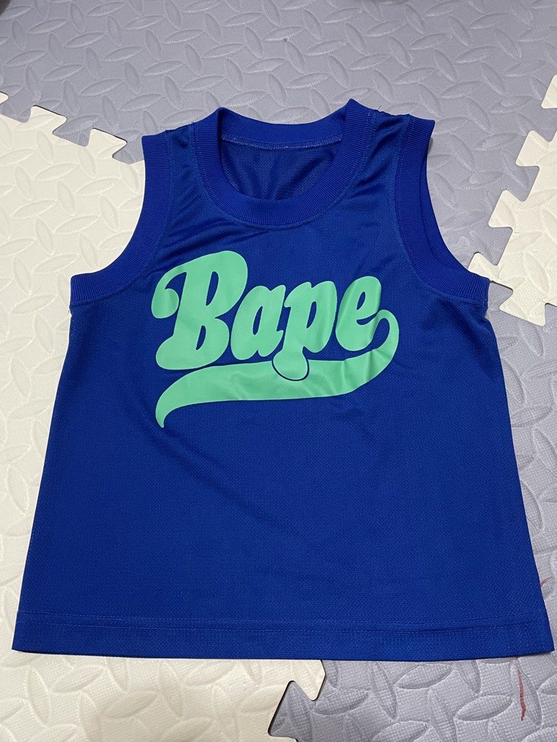 Bape Blue Green Script Logo Tank Top (Category: Babies & Kids Fashion) located in Dagupan City. Submitted by fahionista1988 (Listing ID 1465207862, Image 1). Description: - Color: Bright blue with a large green Bape script logo on the chest - Material: Lightweight mesh-style athletic fabric with ribbed collar and arm openings - Condition: Clean, no marks or pulls - Style: Sleeveless tank top, ideal for casual streetwear.