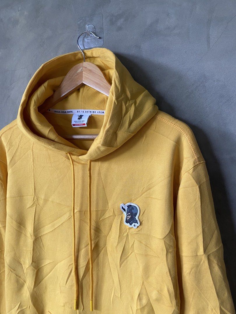 BAPE•Ursus•Izzue Yellow Pullover Hoodie (Category: Coats, Jackets and Outerwear) located in Manila. Submitted by why_notph (Listing ID 1465182770, Image 2). Description: - Brand: URSUS.IZZUE.BAPE (A Bathing Ape) - Color: Bright yellow - Size: XL (interior tag intact) - Features: Monkey graphic chest patch, matching sleeve patch, kangaroo pocket, and drawstrings - Details: Branded interior neck tape and text print on the back of the hood - Conditi