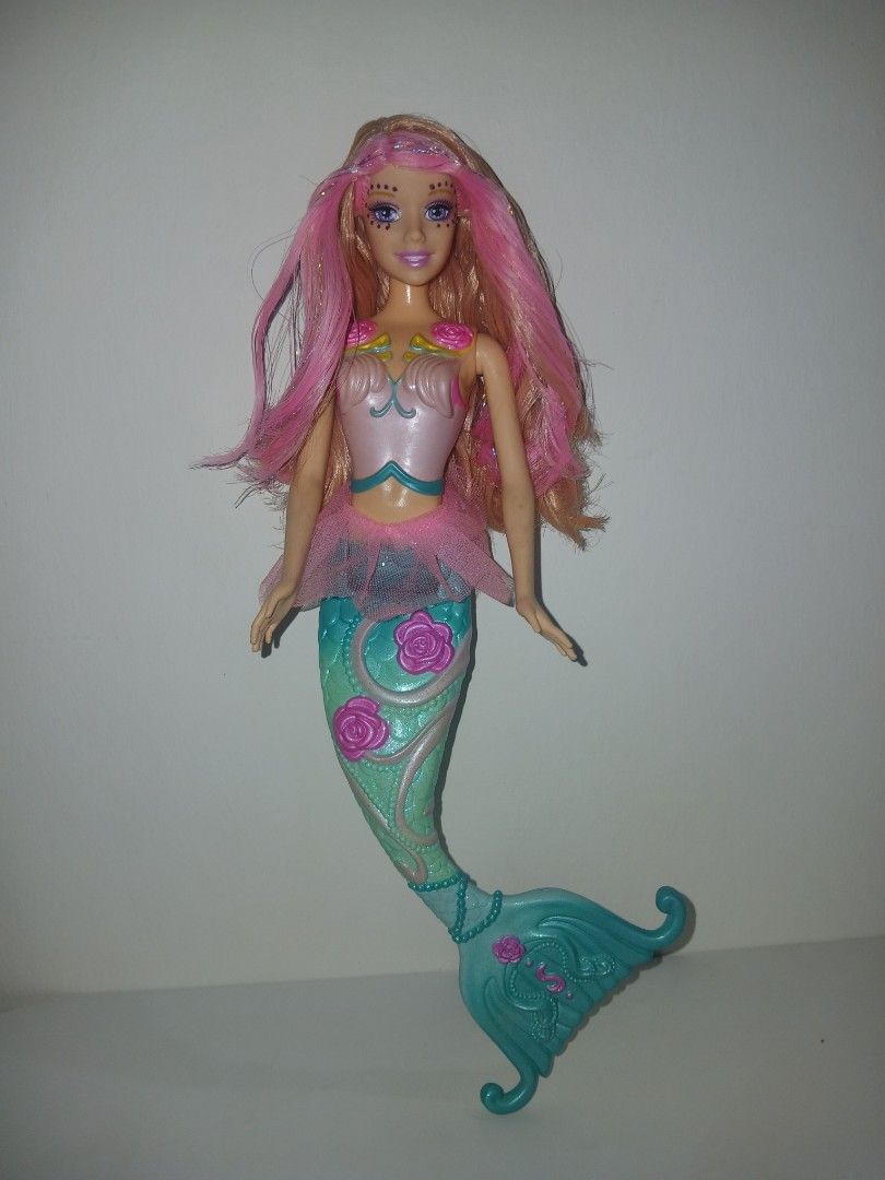 Barbie Shella Fairytopia (Category: Kids Toys) located in Subic. Submitted by frncnjntmr22 (Listing ID 1465358215, Image 1). Description: - Barbie mermaid doll with vibrant pink and blonde streaked hair - Molded pink bodice with cute seashell and rose accents - Elegant sheer pink tulle peplum skirt around the waist - Teal blue tail featuring sculpted scales and pink rose details - Tail fin curves upward with delicate embossed patterns - Beautiful