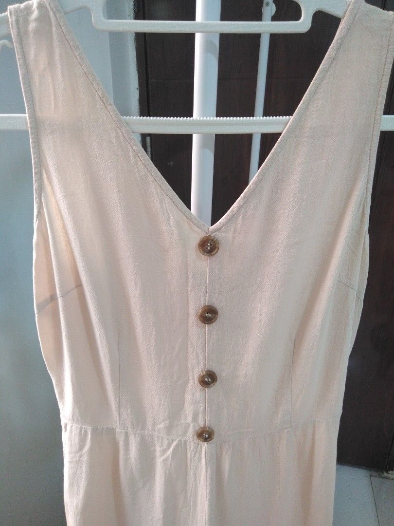Beige V-neck button front cropped jumpsuit (Category: Jumpsuits) located in Marikina City. Submitted by newowners2025 (Listing ID 1465221898, Image 2). Description: Length: 49.5 in Bust: 32-33 in Waist: 24-25 in Hips: 32 in - Color: Beige - Style: Sleeveless jumpsuit with deep V-neckline - Details: Four brown tortoise-shell front buttons - Fit: Wide, cropped pant legs - Fabric: Linen - Lightweight and breathable, perfect for warm weather - Closur