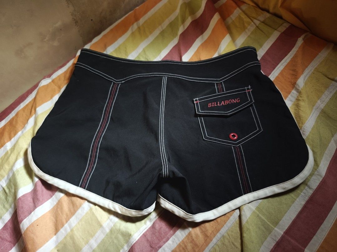 Billabong Black Board Shorts Size 3 (Category: Swim Trunks & Board Shorts) located in Calauag. Submitted by cou1_h (Listing ID 1465338529, Image 1). Description: - Brand: Billabong - Color: Black with pink drawstrings and white piping - Size: 3 (indicated on inner tag) - Material: 100% polyester - Features: Back pocket with snap button closure and logo embroidery on the left leg - Condition: Excellent.