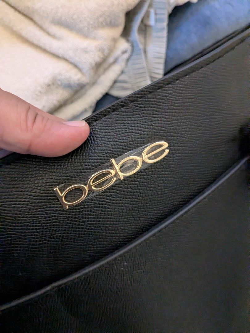 Black Bebe Tote Bag With Gold Hardware (Category: Tote Bags) located in Taguig. Submitted by roxie0419 (Listing ID 1465380346, Image 2). Description: - Brand: bebe - Material: Premium black faux leather with gold-tone hardware and metal logo - Closure: Zip-top closure for added security - Interior: Spacious black fabric lining with 1 zippered pocket and slip pockets - Handles: Sturdy double handles with structured sides - Condition: Clean inside 