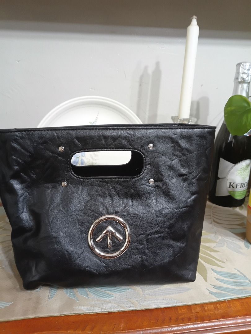 Black structured handbag with silver cut-out handle (Category: Tote Bags) located in Caloocan City. Submitted by harrypotter0215 (Listing ID 1465210384, Image 1). Description: - Style: Structured black handbag with a flat bottom base - Material: Faux leather with a stylish crinkled texture - Handles: Top cut-out handle reinforced with small silver studs - Details: Round silver logo medallion featuring an upward arrow on the front - Interior/Exter