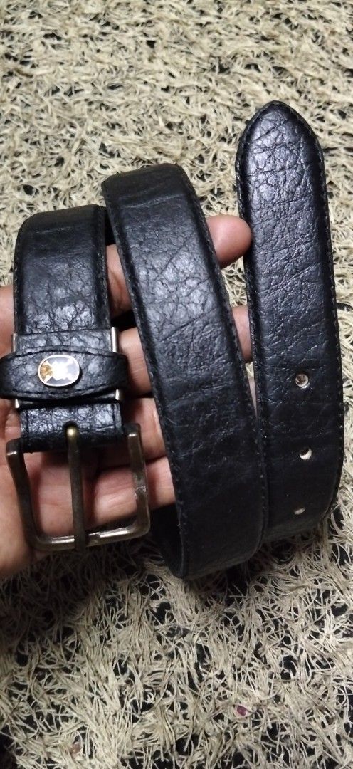 Black Textured Leather Belt with Brass Buckle (Category: Belts) located in Paranaque City. Submitted by michael-08 (Listing ID 1465200587, Image 1). Description: - Color: Black - Material: Genuine leather with heavy pebble grain texture - Hardware: Antique brass-tone metal buckle and single loop keeper - Details: Small circular logo badge on the keeper loop - Fastening: Standard pin buckle with multiple adjustment holes - Style: Classic everyday 