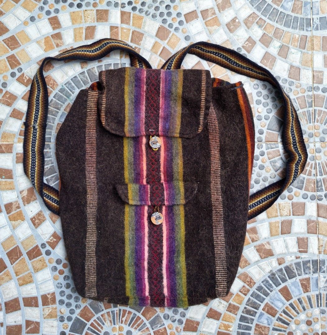 Boho Striped Wool Backpack with Wooden Button Closures (Category: Backpacks) located in Quezon. Submitted by miksxthrift (Listing ID 1465342417, Image 1). Description: - Handmade thick textured wool backpack - Earthy dark brown with vibrant multi-colored vertical stripes - Secure flap closure with carved wooden button - Additional front pouch with matching button detail - Comfortable shoulder straps with patterned woven fabric - Spacious interior