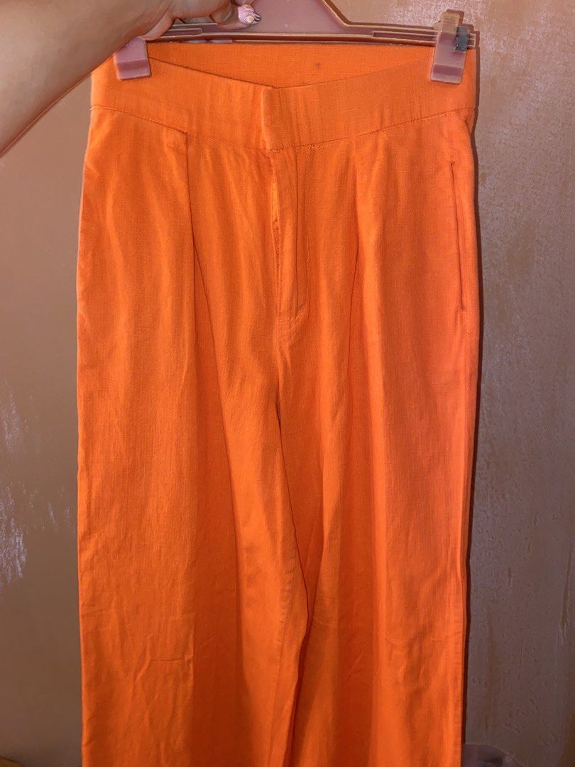 Bright Orange High-Waisted Trousers (Category: Jeans) located in Cavite. Submitted by helloize (Listing ID 1465195574, Image 2). Description: - Color: Vibrant bright orange - Fit: High-waisted with structured waistband - Design: Classic front pleats and functional side pockets - Closure: Zip fly with inner button and hook-and-eye fastening - Styling: Versatile for both casual and dressy outfits *Soft Linen* High waist 24.5in Straight cut Tailored