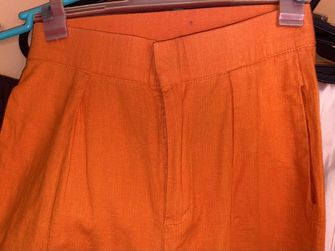 Bright Orange High-Waisted Trousers (Category: Jeans) located in Cavite. Submitted by helloize (Listing ID 1465195574, Image 3). Description: - Color: Vibrant bright orange - Fit: High-waisted with structured waistband - Design: Classic front pleats and functional side pockets - Closure: Zip fly with inner button and hook-and-eye fastening - Styling: Versatile for both casual and dressy outfits *Soft Linen* High waist 24.5in Straight cut Tailored